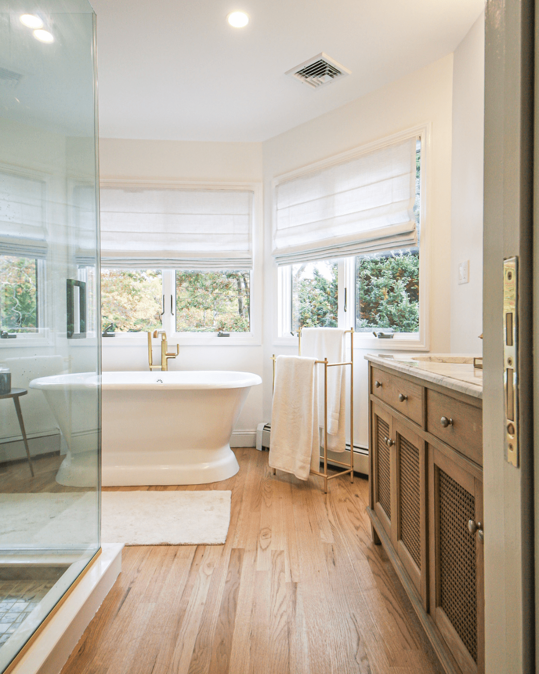 Continuous wood flooring for a cohesive bath design in a master bath renovation.